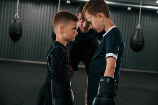 Preparing for the sparring. Young tattooed coach teaching the kids boxing techniques photo
