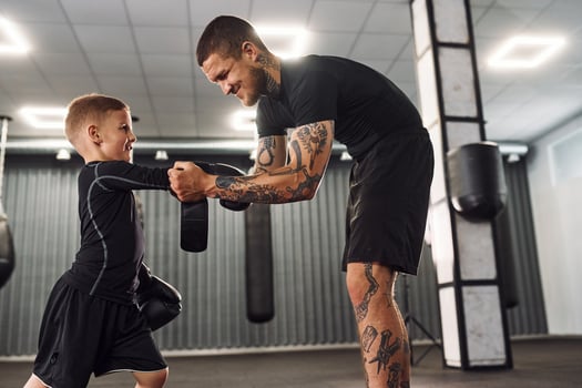 Standing and learning how to punch. .Coach is teaching the boy box techniques indoors photo