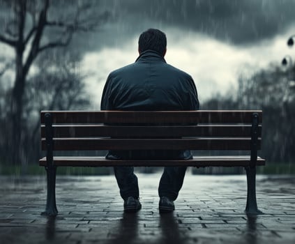 A man sitting on a bench in the rain photo