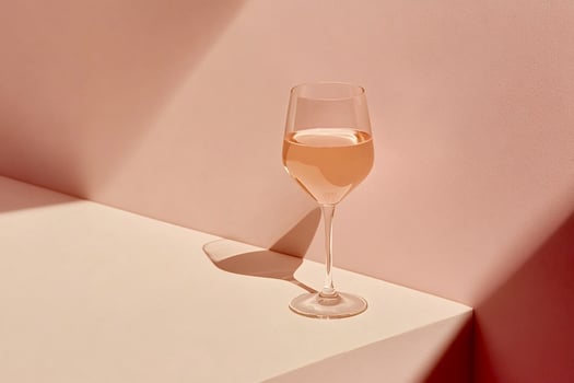 Glass of rose wine standing on corner of table with dramatic lighting photo