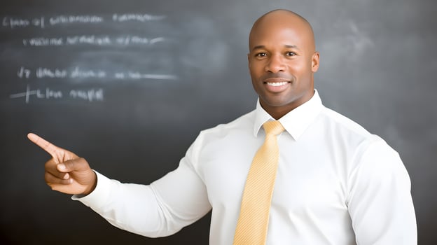 A teacher standing near student pointing to a math problem on a blackboard, classroom interaction photo