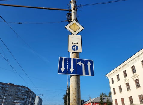 White arrows on a blue background are a standard road sign on a vertical pole against the sky. photo