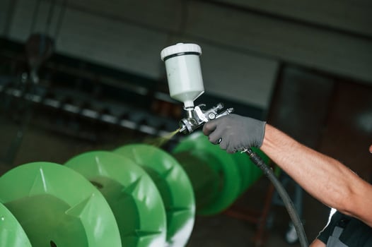 Painting details to green color.. Man in uniform is in workstation developing details of agriculture technique photo