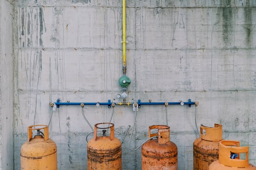 Gas cylinders connected to pipes on a concrete wall photo