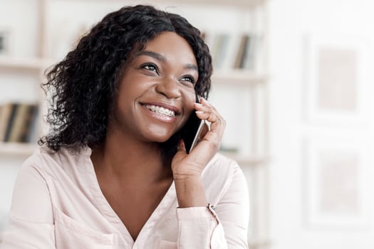 Modern Communication. Joyful black woman with braces talking on cellphone at home, enjoying pleasant conversation, copy space photo