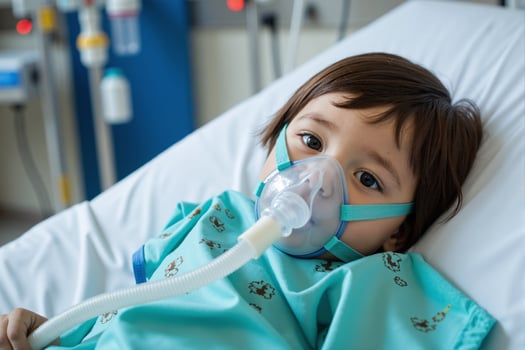 A young child in a hospital bed with an oxygen mask photo