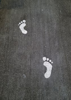 White footprints showing walking direction on asphalt road photo