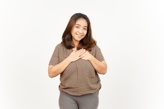 A woman in a brown shirt and gray pants is holding her chest photo