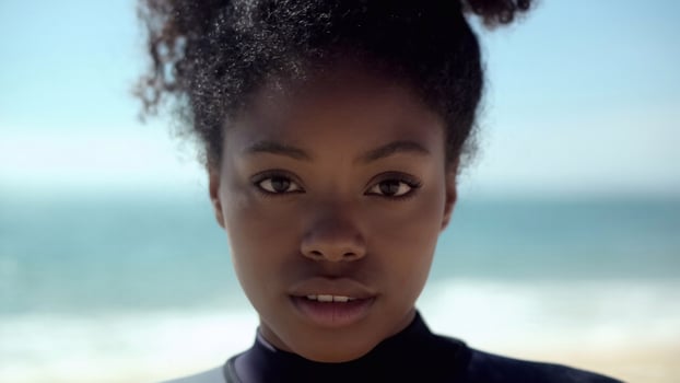 Portrait of a serious black woman in a lifeguard suit, her dark hair gathered back. For media about strong female professionals, rescue team training, beach vacation safety tips photo