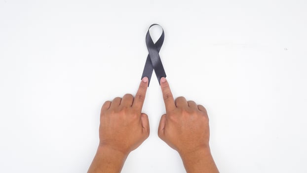 Hands holding long black ribbon as symbol of mourning and melanoma cancer awareness isolated on white background photo