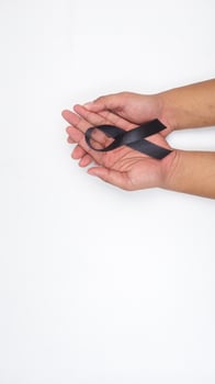 Man hands holding long black ribbon as symbol of mourning and melanoma cancer awareness isolated on white background photo