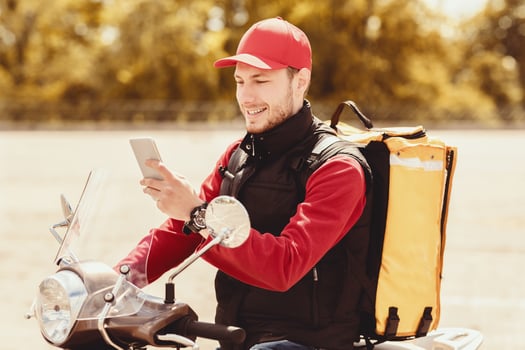 Food Delivery. Professional Courier Using Smartphone Application Delivering Meals On Moto Scooter Outside. photo