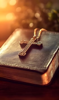 Ornate golden cross lying atop an antique bible, capturing the essence of spirituality photo