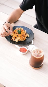 a person eating fries on a plate with a cup of coffee photo