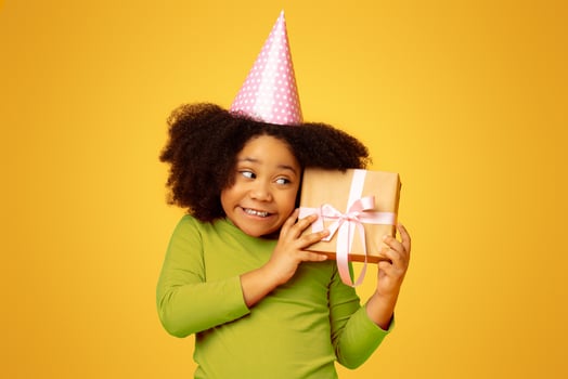 Surprise Gift. Cute Little African American Birthday Girl Shaking Present Box, Trying To Guess What's Inside photo
