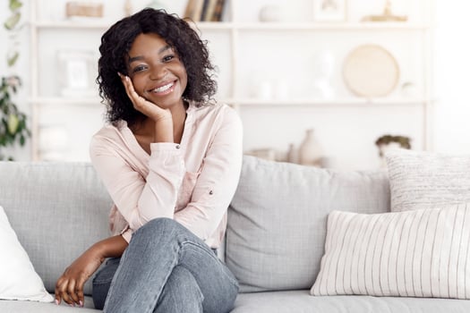 Portrait of beautiful african american woman sitting on sofa. Attractive female relaxing on comfortable couch in living room, enjoying weekend photo