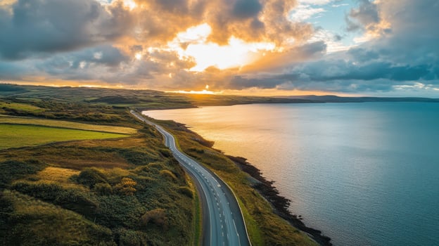 A scenic coastal road winding along a tranquil shoreline at sunset. photo