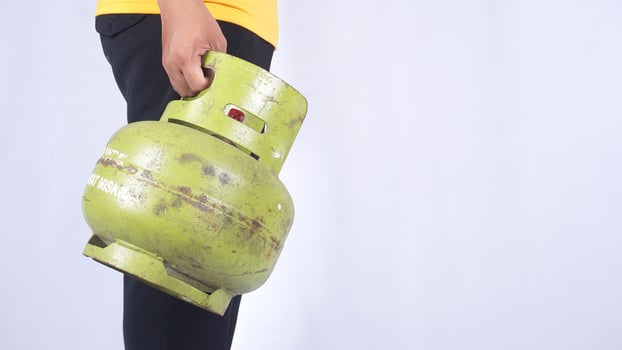 Side view of Asian man holding Indonesia 3kg LPG gas cylinder isolated on white background photo