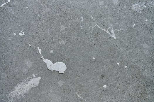 Close-up of concrete wall with white paint splashes and rough texture. Background for construction and renovation concep photo