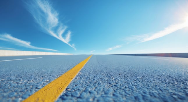 Street view with a yellow center line and clear pavement under a blue sky during daylight hours photo