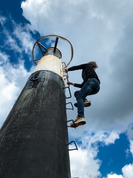 A determined individual, brimming with enthusiasm, skillfully climbs a tall pole with a sturdy ladder, embracing the adventure and courageously facing the challenges of the structure photo