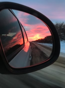 As the sun gradually sets on the horizon, its vibrant and warm colors beautifully reflect in a cars rearview mirror, creating a truly stunning visual experience for all drivers on the road photo