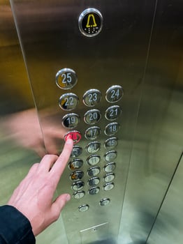 A person is vigorously pressing a bright red button inside the elevator, which is essential for selecting different floors and operating it efficiently for smooth transportation photo