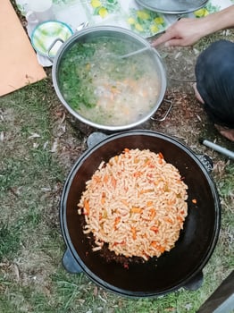 An individual is meticulously cooking a delightful and flavorful meal in a pot placed on the ground, thoughtfully preparing a delicious dish using various fresh ingredients and techniques photo
