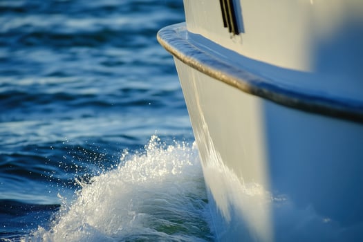 A white motorboat glides through the blue sea, leaving a trail of foamy wake behind. photo