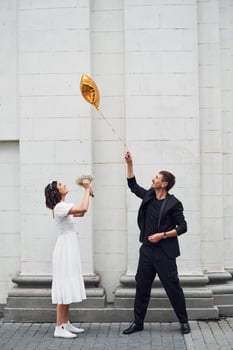 Playing with golden colored baloon. Beautiful bride with his fiance is celebrating wedding outdoors.,. photo