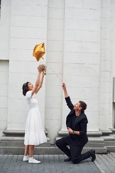 Playing with golden colored baloon. Beautiful bride with his fiance is celebrating wedding outdoors. photo
