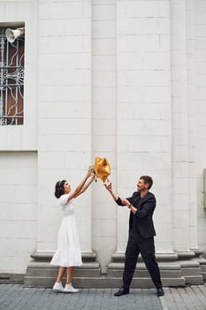 With golden colored baloon. Beautiful bride with his fiance is celebrating wedding outdoors photo