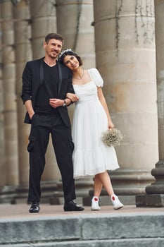 Standing and posing near building. ,.Beautiful bride with his fiance is celebrating wedding outdoors photo