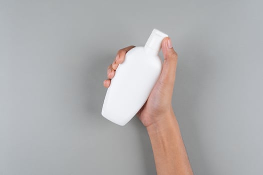Womans Hand Holding Compact Oval Flip-Top Sunscreen Bottle Travel Friendly SPF Background photo