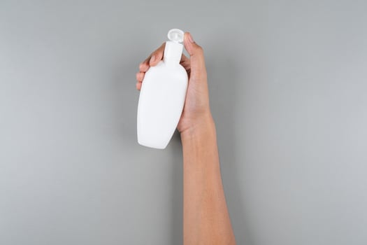 Womans Hand Holding Compact Oval Flip-Top Sunscreen Bottle Travel Friendly SPF Isolated Background photo