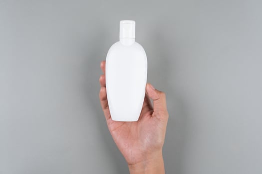 Womans Hand Holding Compact Oval Flip-Top Sunscreen Bottle Travel Friendly SPF photo