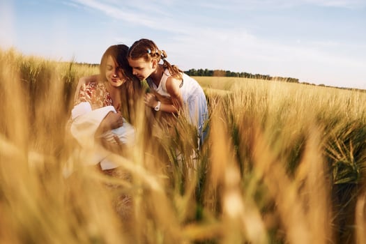 Woman is sitting on the ground. .Mother with her newborn baby and girl is on the field at sunny day together photo