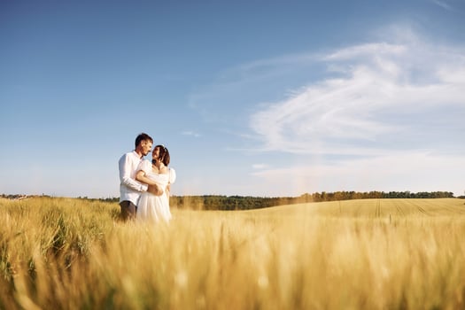 Standing and enjoying the nature. Couple just married. Together on the majestic agricultural field at sunny day photo