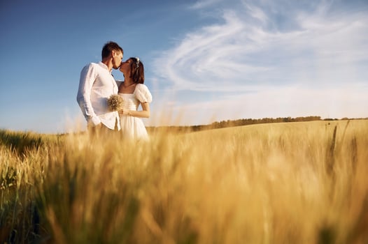 Embracing each other. Couple just married. Together on the majestic agricultural field at sunny day. photo