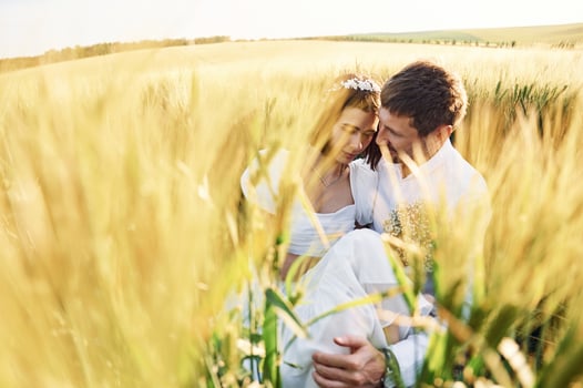 Sitting in the wheat. Happy people. Couple just married. Together on the majestic agricultural field at sunny day photo