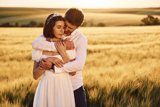 Front view. .Embracing each other. Couple just married. Together on the majestic agricultural field at sunny day photo