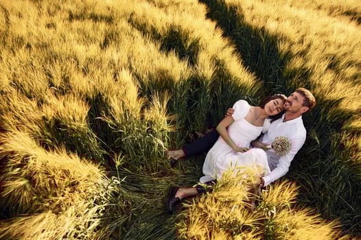 Sitting on the ground. Couple just married. Together on the majestic agricultural field at sunny day photo