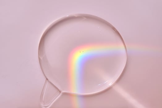 A drop of serum on a pink background with beautiful caustics. photo