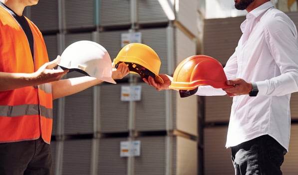 Holding hard hats. Standing together. Two storage workers is in the warehouse photo