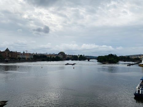 Scenic view of Vltava River with Prague cityscape under a cloudy sky photo
