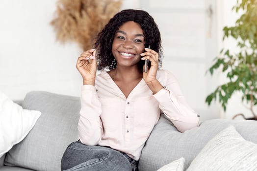 Joyful African Lady Having Phone Call While Relaxing On Couch At Home, Talking With Friends On Cellphone, Enjoying Mobile Communication And Pleasant Conversation, Resting In Cozy Living Room photo