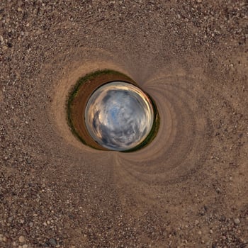A circular hole in the ground with a sky in the middle photo