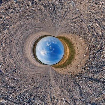 A circular view of a blue sky and dirt photo