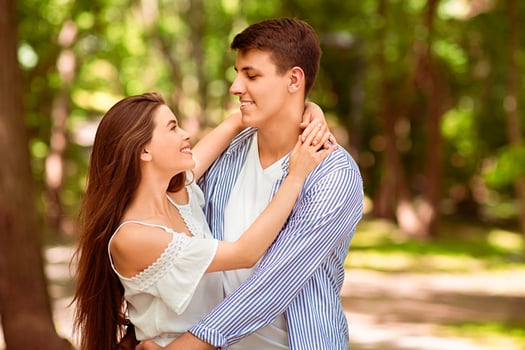 Young married couple embracing each other outside on warm summer day, blank space photo