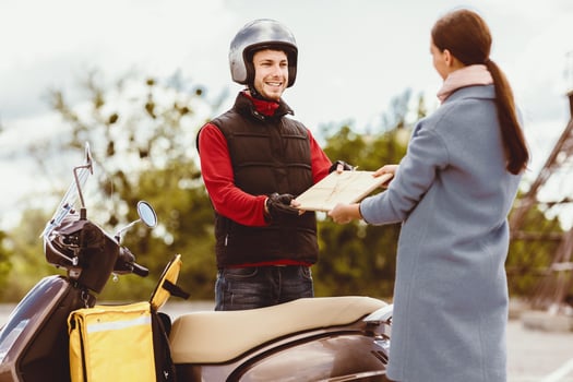 Delivery Concept. Courier Giving Paper Package To Woman Delivering Documents And Restaurant Meals On Scooter Outside. Selective Focus photo